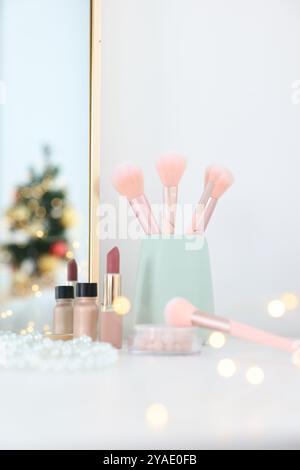 Makeup brushes, cosmetics and mirror on white table indoors Stock Photo