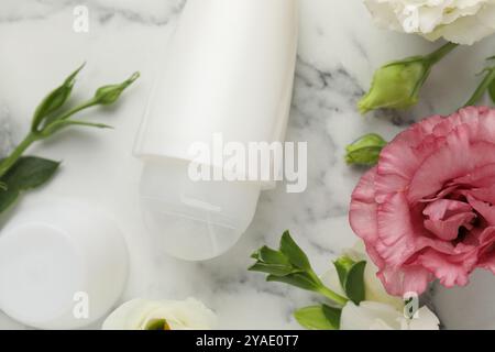 Roll-on deodorant and beautiful eustoma flowers on white marble table, flat lay Stock Photo