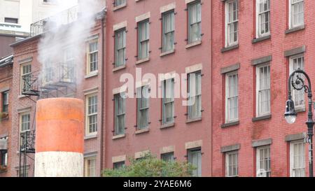 Steam vapor vented on New York City street, orange vapour tube stack. Hot smoke from pipe. Con Edison's Steam Operations system, 5 Fifth avenue Manhattan Midtown architecture. Red brick house, lantern Stock Photo