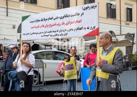 Rome, Italy. 12th Oct, 2024. Two protesters hold up a banner with some words about the use of the death penalty by the 'Iranian regime' and attributed in the sign to Maryam Rajavi during the protest against executions in Iran organized by the National Council of Resistance of Iran in Rome. Some representatives of the Iranian community from Rome and its surroundings demonstrated to raise public awareness against the capital executions of political prisoners in Iran. According to the National Council of Resistance of Iran (NCRI), in the days surrounding the World Day against the Death Penalty, Stock Photo