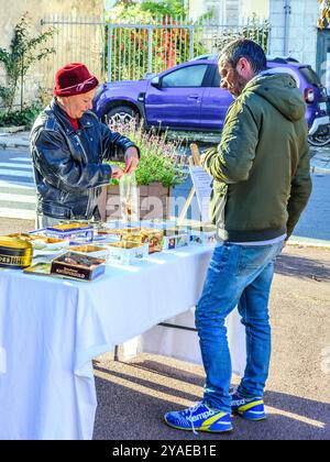 Woman with home-made biscuits and cakes sellin,g to a male customer - Preuilly-sur-Claise, Indre-et-Loire (37), France. Stock Photo