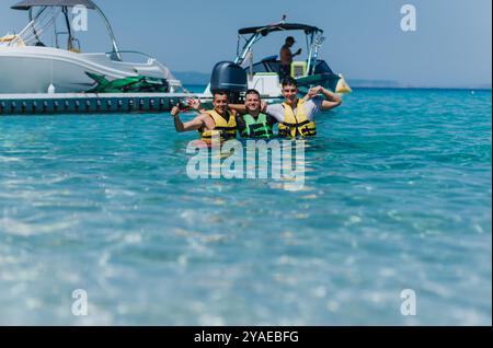 Group of friends enjoying speedboat tubing in clear blue sea on a sunny summer day Stock Photo