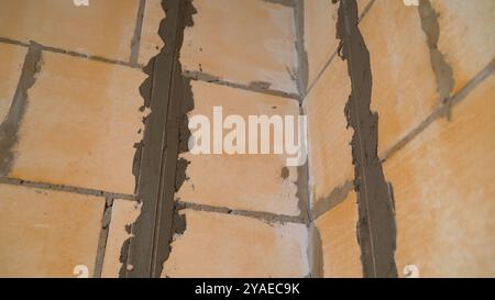 Construction worker is applying cement glue plastering on the brick wall by using spatula at the construction site. Stock Photo