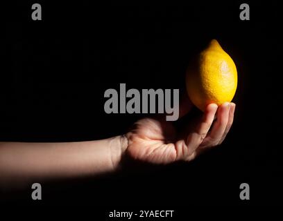 lemon in hand on black background Stock Photo