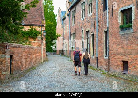 Young couple walks through a narrow street in the Begijnhof - Groot Beguinage, in the city of Leuven in Belgium. Stock Photo