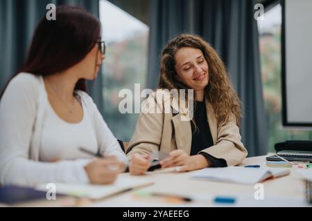 Two young women engaged in collaborative studying in a classroom Stock Photo