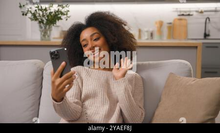 Happy smiling African american woman talking mobile phone smartphone online virtual meeting ethnic girl cheerful waving hand greeting record blog Stock Photo