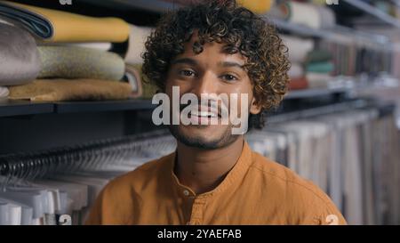 Arabian Indian ethnic man customer salesman fashion designer tailor stylist in fabric shop textile store happy male owner small business atelier Stock Photo