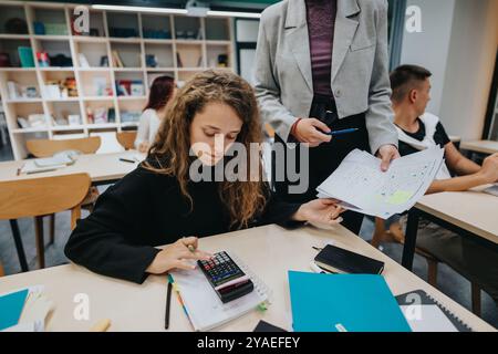 Engaged students learning in a modern classroom setting with a teacher Stock Photo
