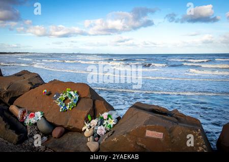 floral tributes on rocky shoreline and breaking waves on cambois beach near blyth northumberland Stock Photo