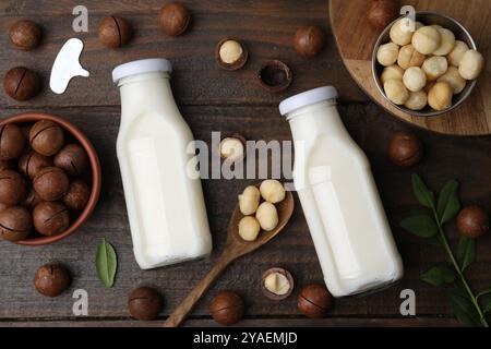 Bottles of macadamia milk and nuts on wooden table, flat lay Stock Photo