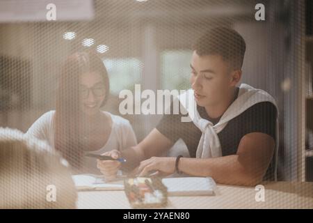 Students collaborating on project in library setting through window Stock Photo