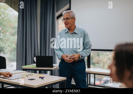 Elderly professor engaging with students in classroom setting Stock Photo