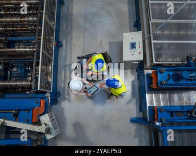 Female manager talking with two workers on the factory line, including one with a disability, about the production process, aerial shot. Stock Photo