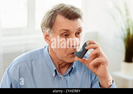 Elderly man using asthma inhaler for allergies Stock Photo