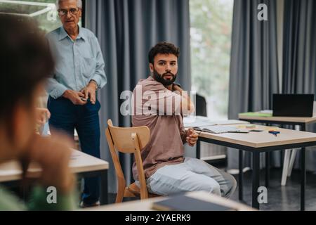 Elderly professor engaging with students in modern classroom setting Stock Photo