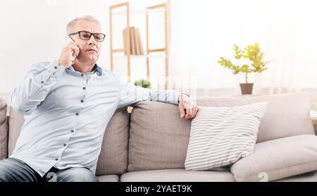 Serious mature man talking on mobile phone at home Stock Photo