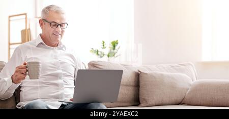 Elderly Man Using Laptop And Having Coffee Stock Photo