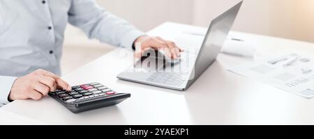 Mature man using laptop and calculator at office Stock Photo