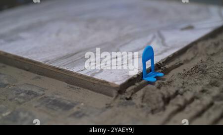 Construction worker laying ceramic tile using tile leveling system. Stock Photo
