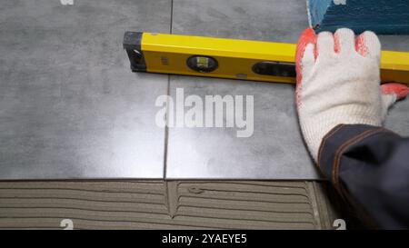 Construction worker leveling floor tiles using spirit level. Stock Photo