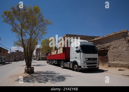 Large white lorry truck with loaded goods on red trailer over blue sky in small town of South America. Transportation vehicle, transportation concept. Stock Photo