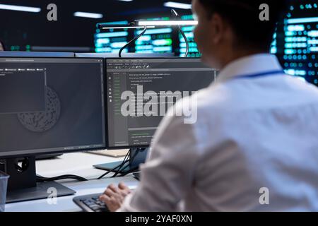 Programmer in server farm checking recovery plan, monitoring data center energy consumption. Employee in server room making sure sensors are functioning optimally, doing routine disk checks using PC Stock Photo