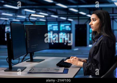 Software developer in server hub checking recovery plan, monitoring data center energy consumption. Indian woman in server room making sure sensors are functioning optimally, doing routine disk checks Stock Photo