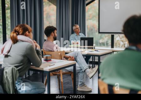 Students engaged in classroom lecture with elderly professor Stock Photo