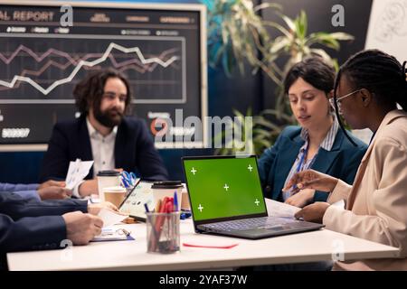 Project team developing strategies with mockup screen on laptop, sharing details and project goals, expressing concerns. Firm employees collaborating on organizational growth. Stock Photo