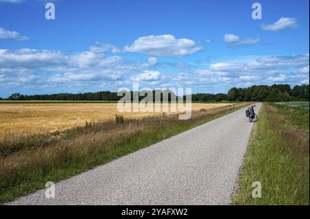 Norg, Drenthe, The Netherlands, 07 20 2022, Road through the green and yellow and green fields over blue sky at the Dutch countryside, Europe Stock Photo