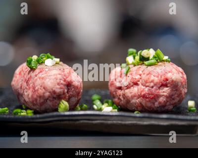 Japanese Wagyu meat ball teppanyaki in a plate before cooking, chopped scallion srpinkled on top of it, Stock Photo