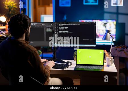 Programmer using isolated screen laptop to secure company servers from virus attacks. IT remote employee writing code, building firewalls protecting data using chroma key notebook Stock Photo