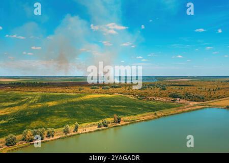 Drone pov aerial shot of wildfire burning in countryside landscape, thick white grey smoke rising up in the air, selective focus Stock Photo