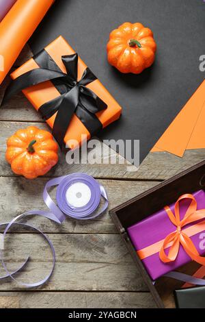 Halloween decorations with gift boxes, wrapping paper and ribbons on brown wooden background Stock Photo