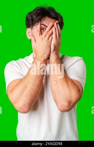 Surprised young man with a beard expressing shock against a bright green background Stock Photo