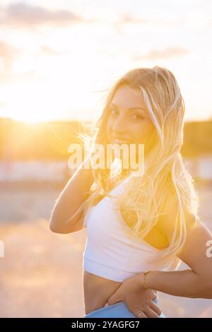 Young blonde woman is taking a break and posing after her workout, enjoying the sunset Stock Photo