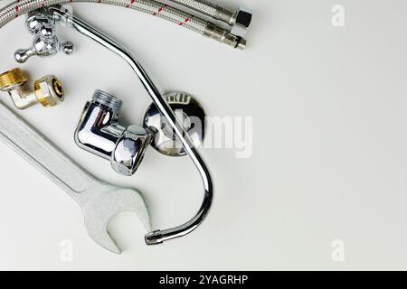 A sleek wrench is casually laying on a pristine white surface right next to a shiny faucet, creating a stark and intriguing contrast Stock Photo