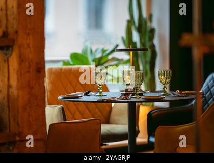 Round served table ready for guests. Round decorated table with empty plate, glasses, forks, napkin. Elegant dinner table. Stock Photo