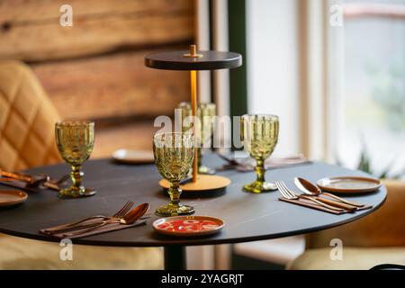 Round served table ready for guests. Round decorated table with empty plate, glasses, forks, napkin. Elegant dinner table. Stock Photo