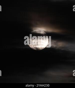 Clouds moving across full moon against black night sky. Stock Photo