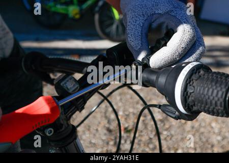 Close-up view - hands in gloves turning a screw on a bicycle Stock Photo
