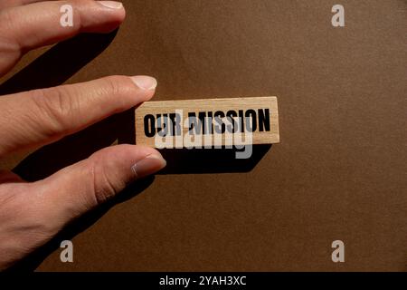 Our mission message written on wooden block with brown background. Conceptual our mission symbol. Copy space. Stock Photo