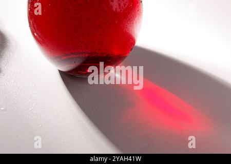 glass bottle with red vine on white table, close-up, real shadows Stock Photo