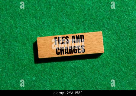 Fees and charges message written on wooden block with green background. Conceptual fees and charges symbol. Copy space. Stock Photo