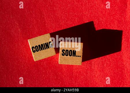 Coming soon message written on wooden cubes with red background. Conceptual coming soon symbol. Copy space. Stock Photo