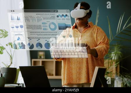 African American female remote worker using VR business application to study fresh statistics Stock Photo
