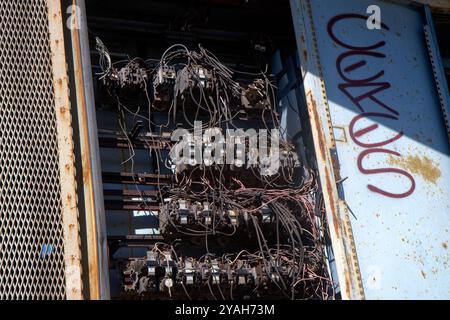 Abandoned Electrical Panel with Exposed Wires and Graffiti Stock Photo