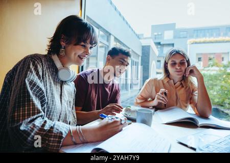 High school friends bonding over a study session on a city campus. They are smiling and engaged in collaborative learning in a modern environment. Stock Photo