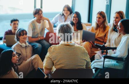 A multigenerational learning group with students engaged in a collaborative session, highlighting diversity and knowledge sharing in a modern, bright Stock Photo